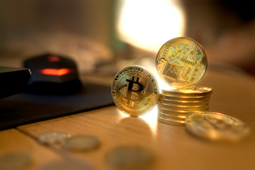 Golden Bitcoin cryptocurrency lies on the wooden table and shine like a diamond in the darkness. 