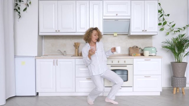 People And Technology Concept. Happy Woman With Smart Phone, Dancing And Smiling In Kitchen