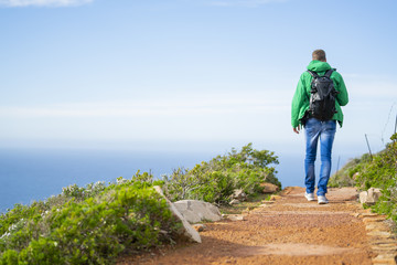Naklejka premium Young man is walking along a beautiful hiking trial at Cape Point, South Africa