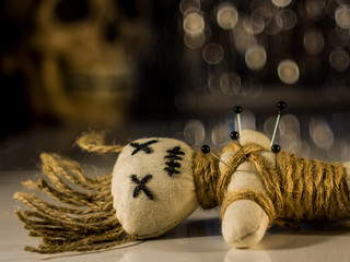 a needle punched voodoo doll lies on a table