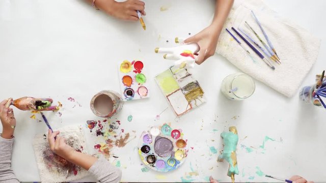 Step by step. Little girls painting paper mache unicorn with acrylic paint