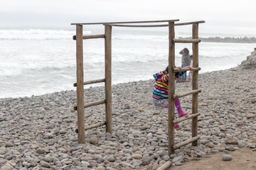 Cute little girl with colorful sweater playing on the beach