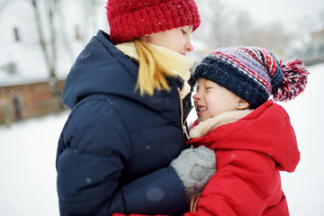 Two adorable little girls having fun together in beautiful winter park. Beautiful sisters playing in a snow.