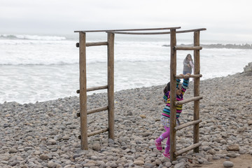 Cute little girl with colorful sweater playing on the beach