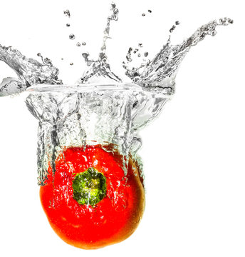 Red bell pepper dropped into liquid creating creative splash