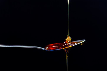 Golden maple syrup dropped onto a spoon - obrazy, fototapety, plakaty