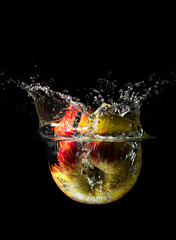 An apple dropped into liquid creating a beautiful splash