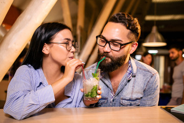 Couple drinking cocktail from same glass