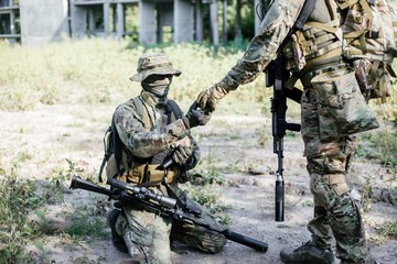 Military soldier in camouflage in the war giving ammunition to his friend