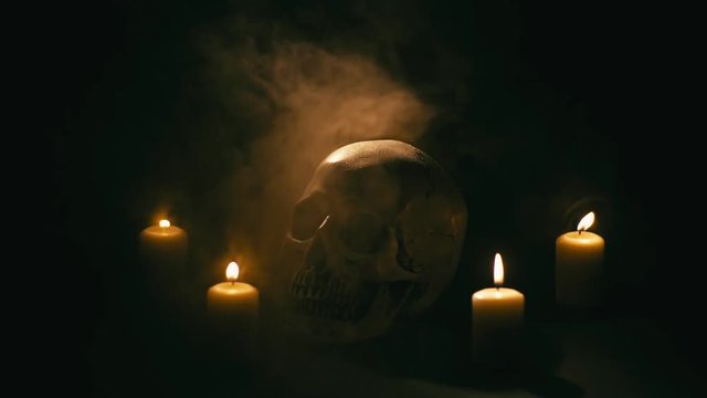 Skull between candles with smoke, halloween theme