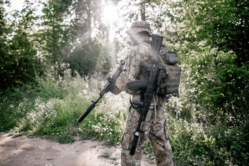 Soldier in camouflage uniform with a rifle in the woods