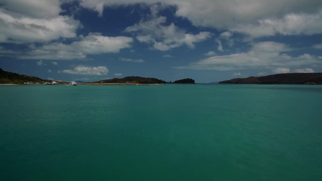 Blick vom Schiff auf ein fahrendes Boot mit Insel im Hintergrund