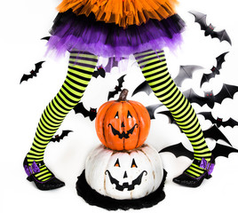 Funny green black Striped legs of a little girl with halloween costume of a witch with witch shoes and smiley halloween pumpkin jack o lantern