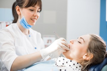 Fototapeta premium Dentist in white uniform examines the oral cavity of the patient