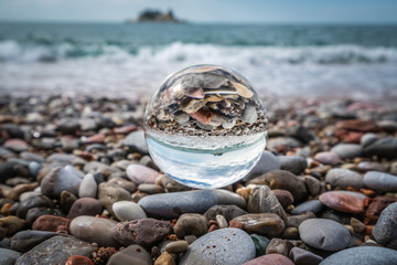 Beach peebles reflected in a galss ball