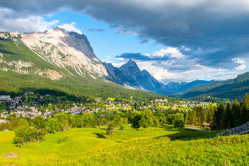 Obraz premium Panorama of Cortina d'Ampezzo with green meadows and alpine peaks on the background. Dolomites, Italy