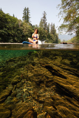 Over and Under picture of a woman paddle boarding in a river during a vibrant sunny summer day....