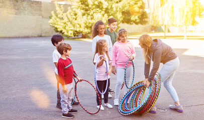 Kinder machen Sport auf Schulhof mit Reifen