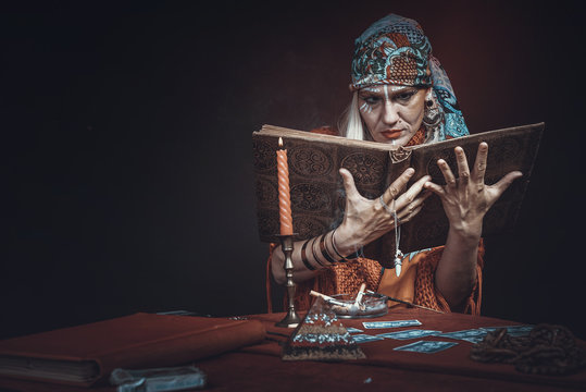 Folklore gypsy tribal soothsayer, chanting spell from her spellbook