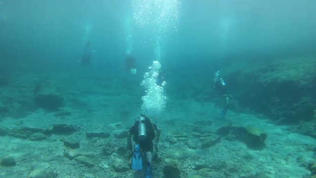 Scuba divers going through a shallow gully in the Mediterranean.