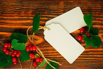 Mock up, white labels and sheets of paper with red berries and green leaves on wooden brushed...