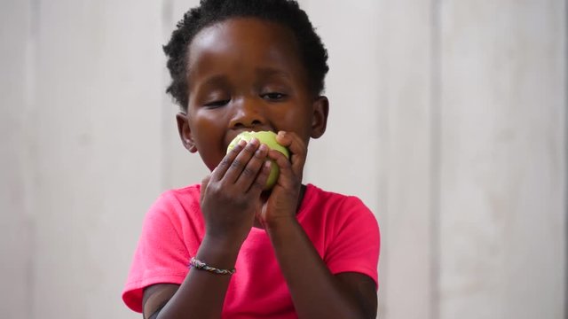 Cute African girl eating an apple