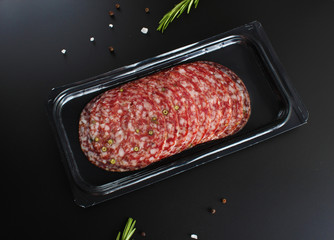 sausage sliced in a package on a dark background