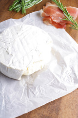 cheese brie and prosciutto jamon ham wooden background rosemary