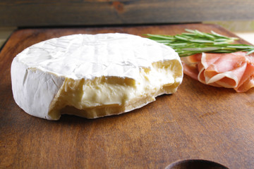 cheese brie and prosciutto jamon ham wooden background rosemary