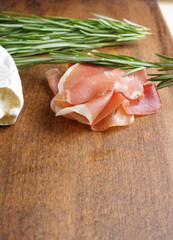 cheese brie and prosciutto jamon ham wooden background rosemary
