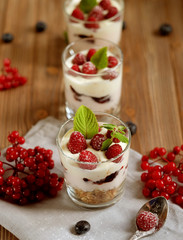 Healthy breakfast - yogurt with fresh berries and muesli served in glass jar, on wooden background, close up