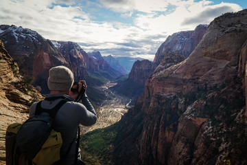Fototapeta premium Adventure photographer capturing the valley of Zion National Park from atop of Angels Landing