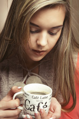 portrait of a beautiful woman with a cup of coffee standing on the beige background, close up