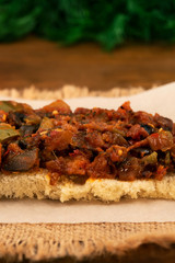 Vegetable stew on a thin piece of white bread on the background of dill leaves, vertical frame, close-up.