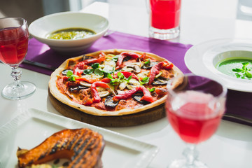 Table in cafe with vegetarian dishes - pizza, grilled pumpkin, pie and sweet drinks.