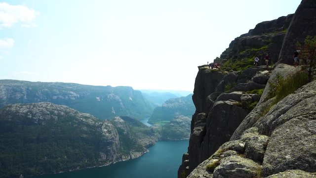 Side view of Preikestolen with tourists walking on the path in Norway.