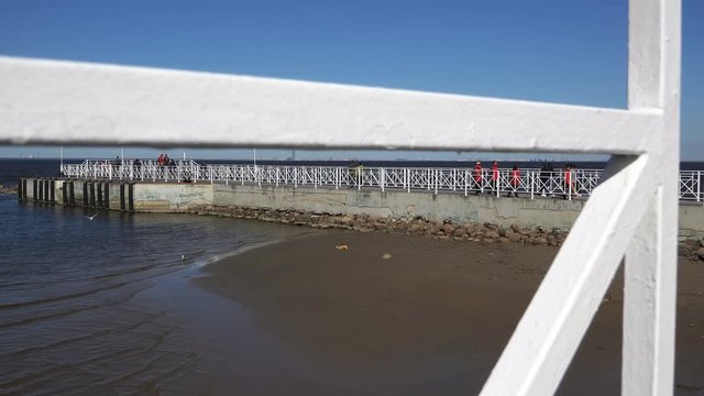small waves approach the shore at the pier.