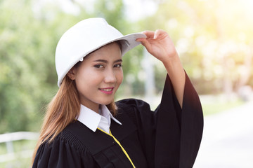 Beautiful Attractive Asian Student Graduate woman in gown smile with engineer white helmet so proud and happiness,Education Concept
