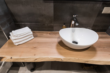 Modern interior of the bathroom. The washbasin is made of white massive shell on the table of wood. Minimalism and simplicity in a bright grey functional interior. Top view