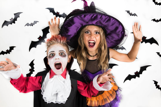 Halloween kids: little girl and boy dressed up in Halloween costumes of witch and vampire Dracula for pumpkin patch and Halloween party