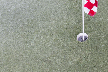 Close up of golf driving range. Hole and red flag on green grass.