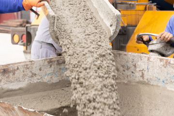 Pouring Ready-mixed concrete flows out of the mixing mobile the concrete mixe into the dumper truck for transport further into a small area.