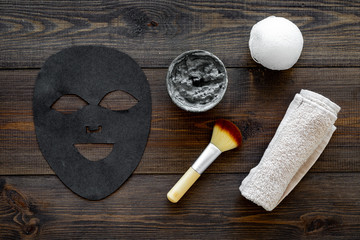 Black facial mask for face spa. Black head remover mask. Mask with clay on dark wooden background...