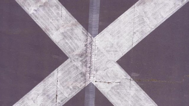 Drone overhead shot of letter X painted on a runway. Slow rise to reveal X on the runway. 4K inspire 2 footage shot with X5S camera with a 15mm lens.