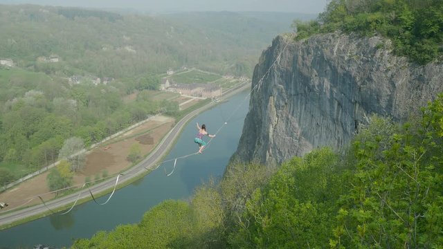 Cinematic amazing woman slack line high line tight rope walking in mountains