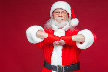 Christmas. Santa Claus with red bandages wound on his hands for boxing imitates kicks. Kickboxing, karate, boxing. Isolated on red background.