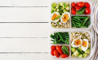 Vegetarian meal prep containers with eggs, brussel sprouts, green beans and tomato. Dinner in lunch box. Top view. Flat lay
