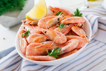 Boiled  shrimps or prawns on a white bowl on a white table. Seafood.