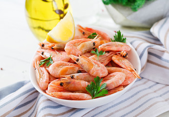 Boiled  shrimps or prawns on a white bowl on a white table. Seafood.
