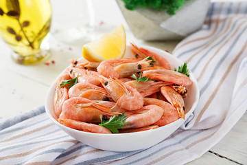 Boiled  shrimps or prawns on a white bowl on a white table. Seafood.